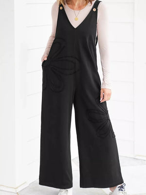 Black cotton wide-leg maternity romper with floral appliqué detail and button straps.