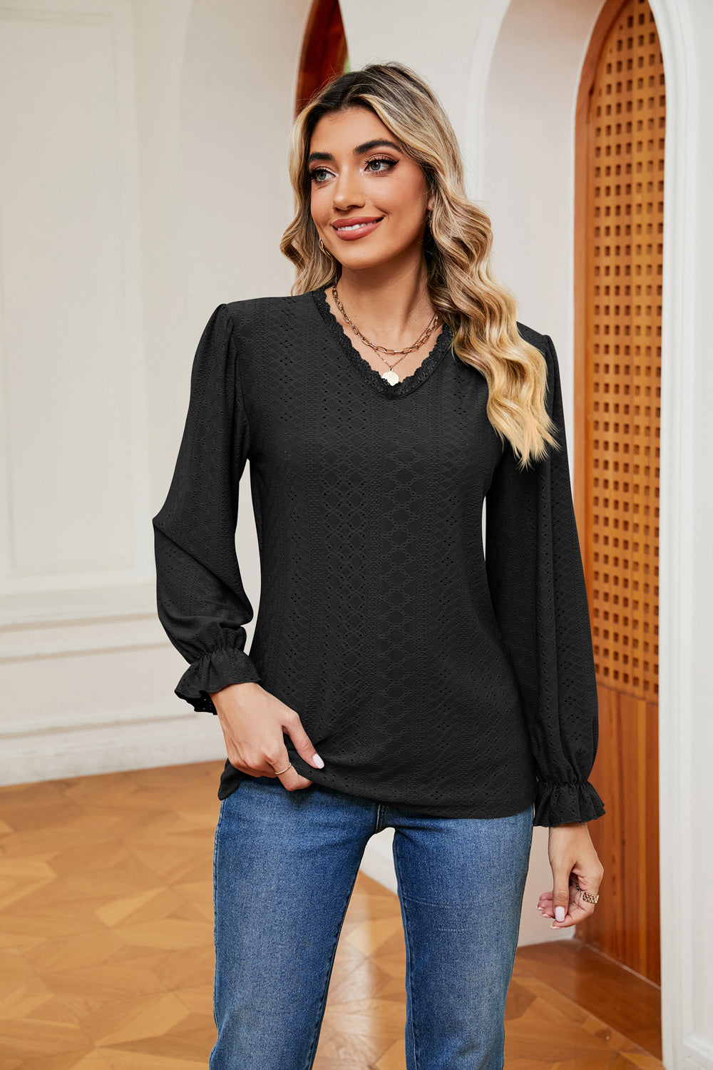 Black perforated sleeve blouse with V-neck and ruffle cuffs.