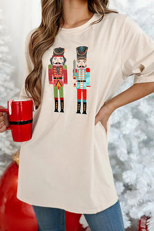Tan oversized graphic tee with two embroidered nutcracker soldiers, crew neck, short sleeves.