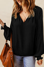 Black blouse with V-neck and ruched cuff voluminous sleeves.