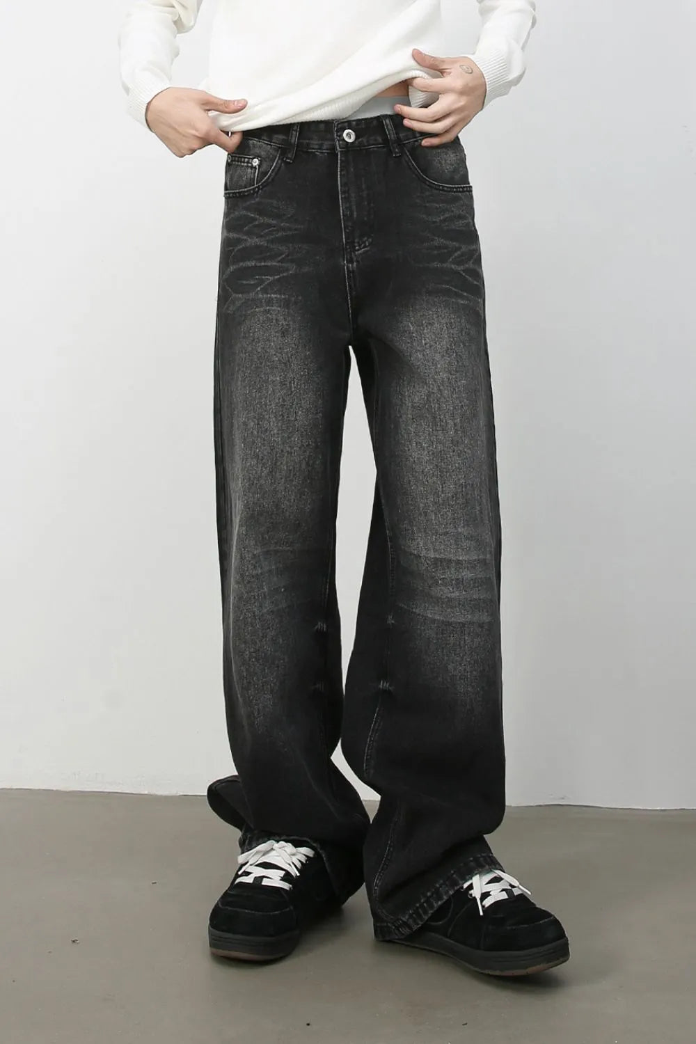 Dark wash distressed denim jeans with a wide-leg silhouette and cat's whisker detailing.