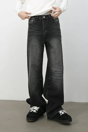 Dark wash distressed denim jeans with a wide-leg silhouette and cat's whisker detailing.