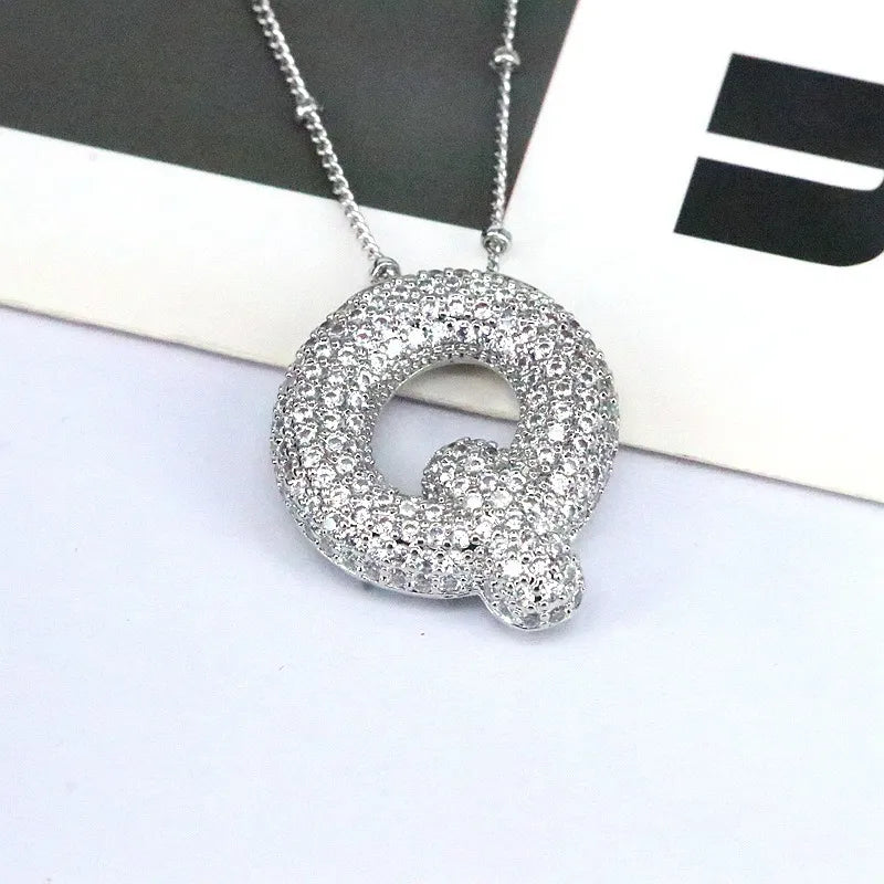 Pave initial pendant necklace with alphabet Q charm on a beaded chain.