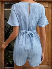 Light blue textured romper with flutter sleeves, tie waist, and keyhole back.