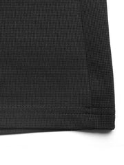 Black textured knit jumpsuit detail showing waffle weave fabric and hem.