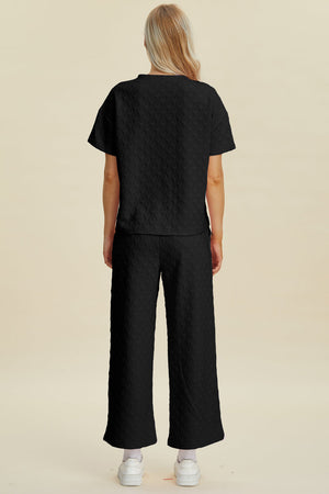 Black textured knit lounge set with wide leg pants and short sleeve top.