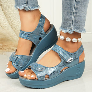 Sky blue textured wedge sandals with adjustable straps and contrast stitching.