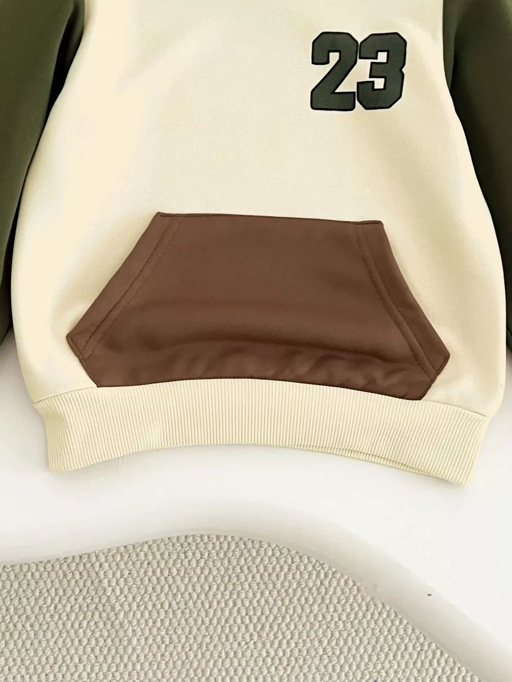 Color block baby hoodie with brown pocket and green 23 graphic.