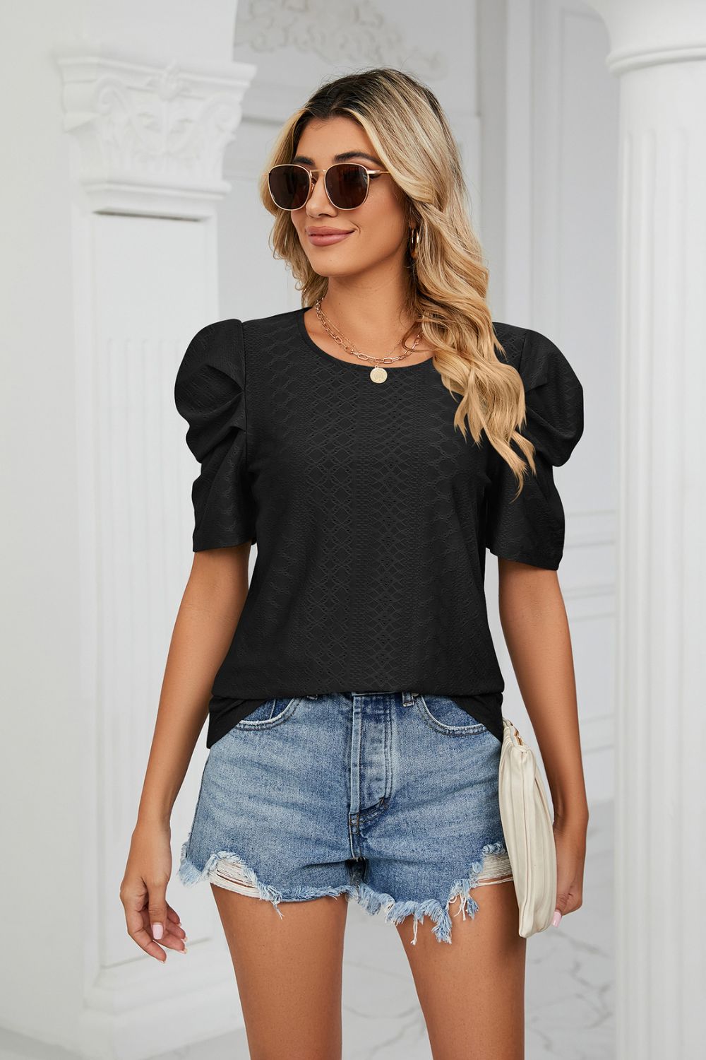 Black perforated sleeve volume top with textured fabric and round neckline.