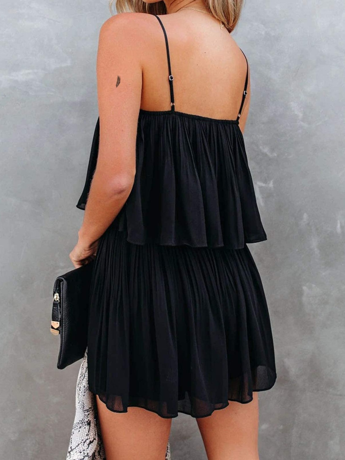 Black tiered cami romper with delicate straps and a flowy, pleated skirt.