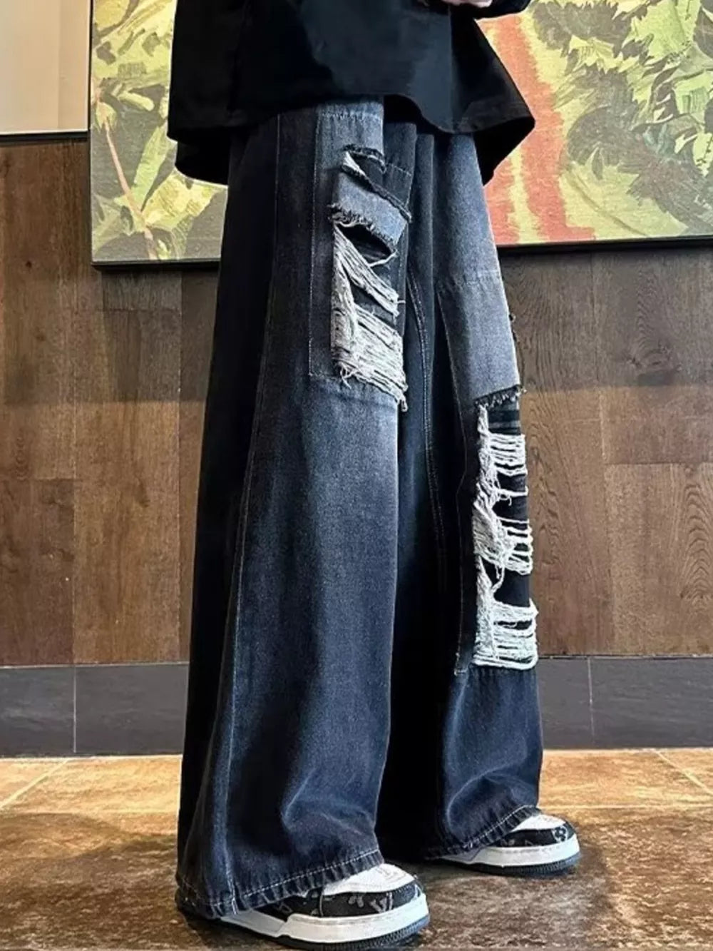 Relaxed fit dark wash denim jeans with distressed rips and patchwork details.