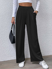 Black wide leg trousers with pleated front and pockets, styled casually.