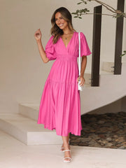 Hot pink midi dress with puff sleeves, V-neck, tiered skirt, and cinched waist.