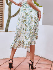 Asymmetric wrap skirt with leaf print and ruffled hem, styled with black heels.