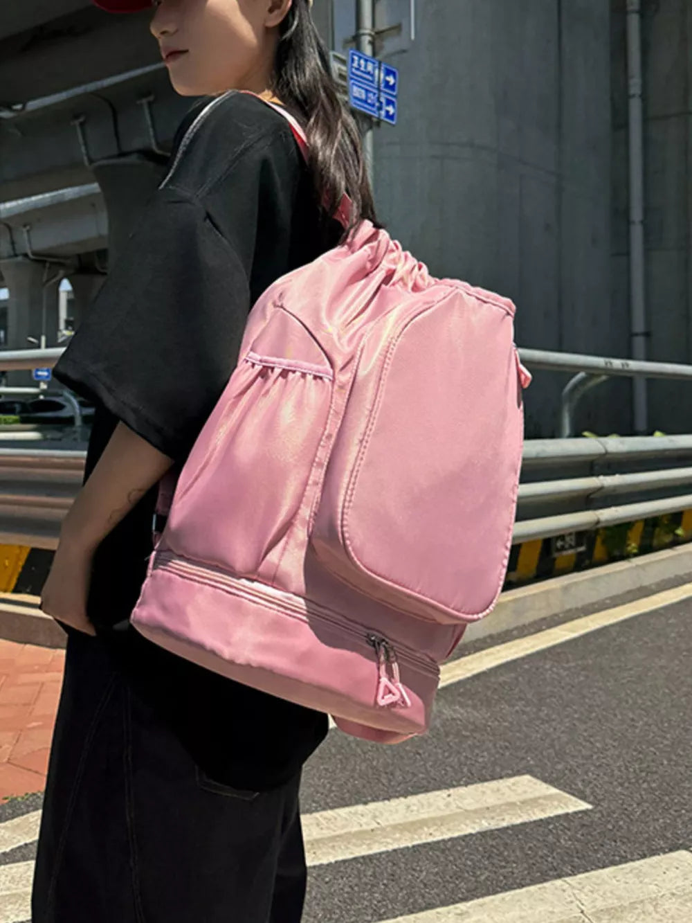 Blush pink drawstring duffle bag with zippered bottom compartment and side pockets.