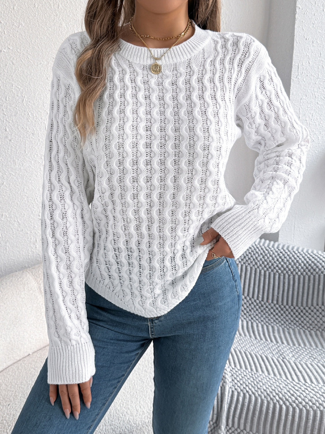 White acrylic cable knit sweater with asymmetric hem and crew neck.