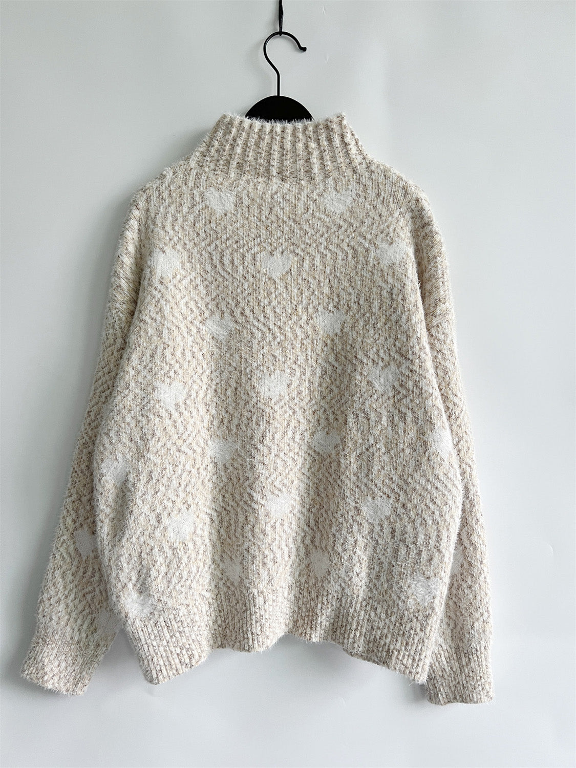 Textured acrylic turtleneck sweater in cream with a subtle heart motif pattern.