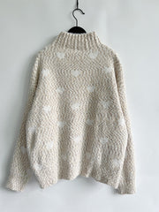 Textured acrylic turtleneck sweater in cream with a subtle heart motif pattern.