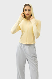 Light yellow active hoodie with thumbholes and zipper, worn by a model.