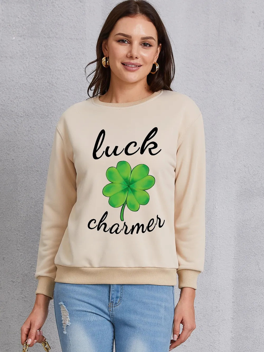 Khaki crewneck sweatshirt with green shamrock graphic and "luck charmer" text.