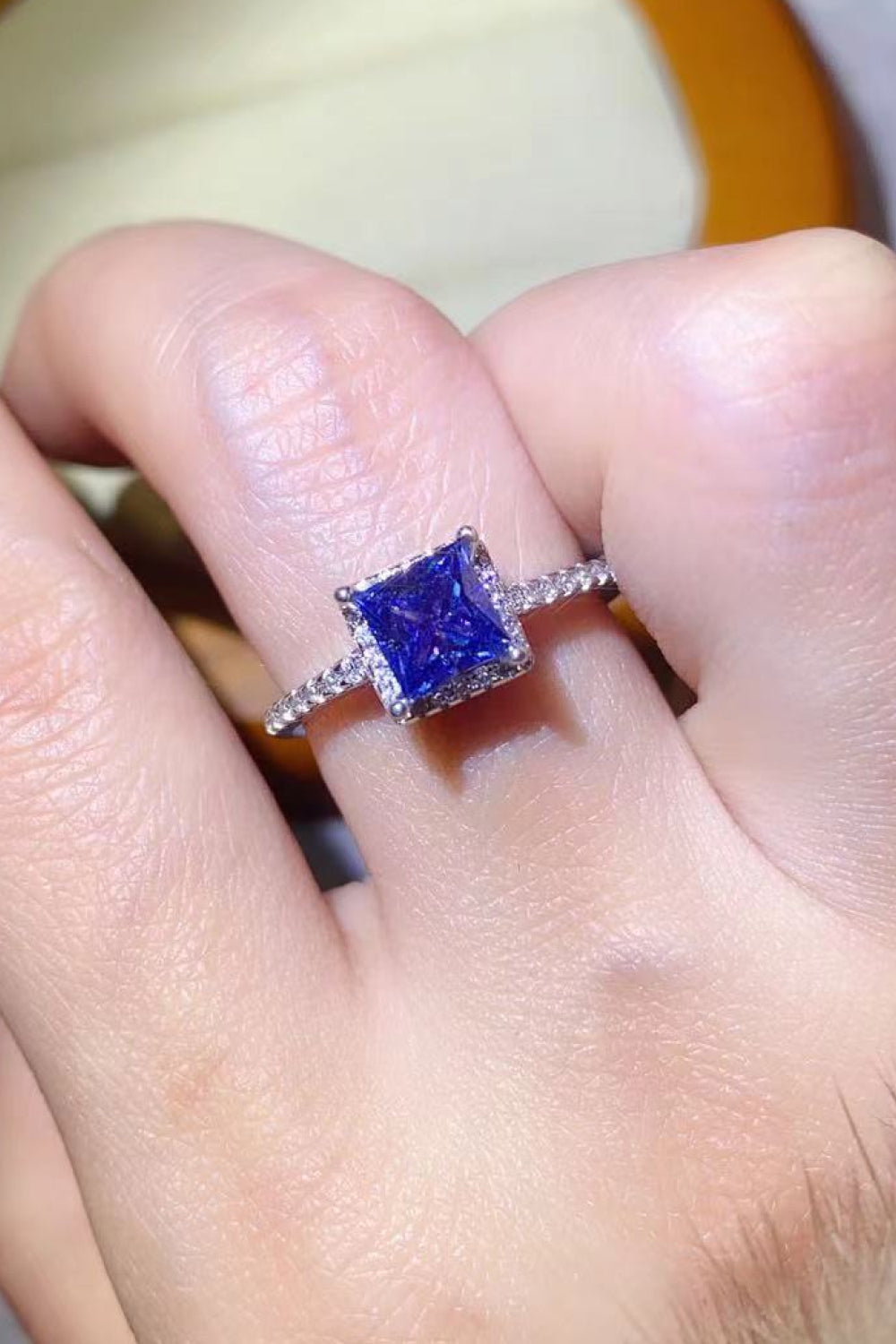 Blue square halo ring with pave band on finger