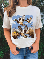 Cream cotton short-sleeve tee with a graphic print of ducks flying over water and reeds.