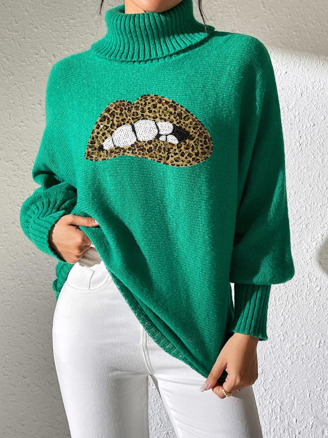 Green turtleneck sweater with sequin lip detail and leopard print accents.