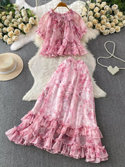 Pink floral ruffle set with bow detail, featuring a short sleeve top and a tiered maxi skirt.
