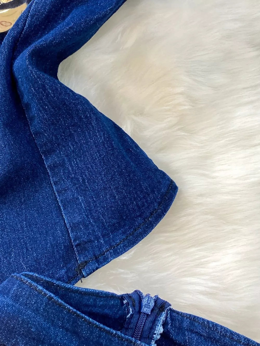 Dark blue cotton denim vest detail with zipper closure on flare jeans.