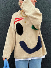 Tan knit sweater with abstract graphic face, red stripes, black eye, green accent, and blue smile.