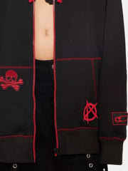 Black zip-up hoodie with red skull, anarchy, and safety pin patches and contrast stitching.