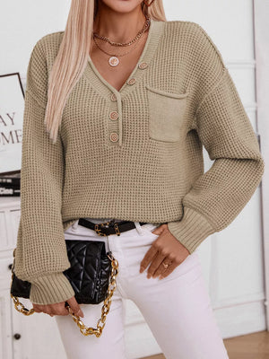 Relaxed knit sweater with V-neck, button placket, and chest pocket in a neutral color.