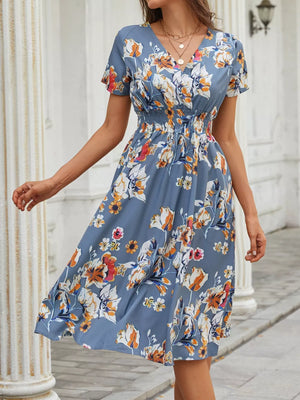 Blue gray midi dress with vibrant floral pattern, v-neck, short sleeves, and smocked waist.