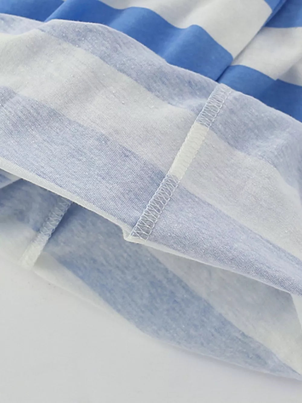 Blue and white striped cotton t-shirt hem detail with visible stitching.