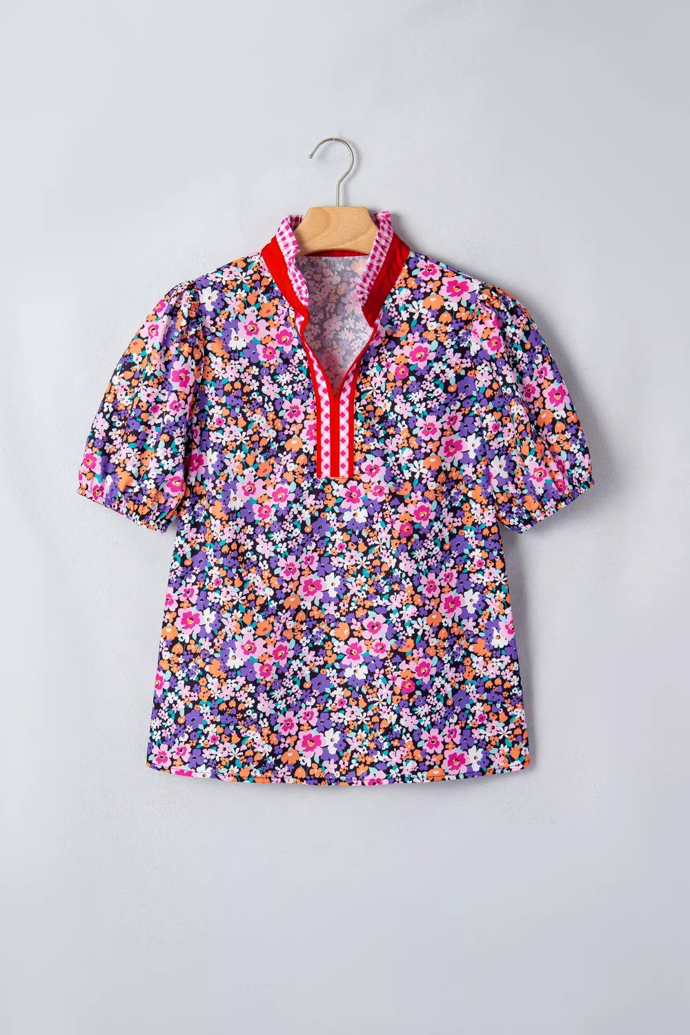 Floral print polyester shirt with v-neck, puff sleeves, and plaid trim detail.