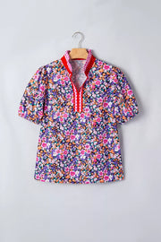 Floral print polyester shirt with v-neck, puff sleeves, and plaid trim detail.