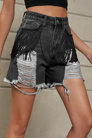 Black distressed denim shorts with fringe pockets and raw hem.