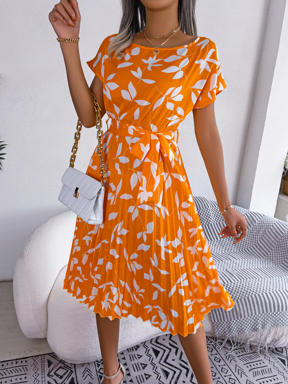 Orange leaf print midi dress with short sleeves, tie waist, and pleated skirt.