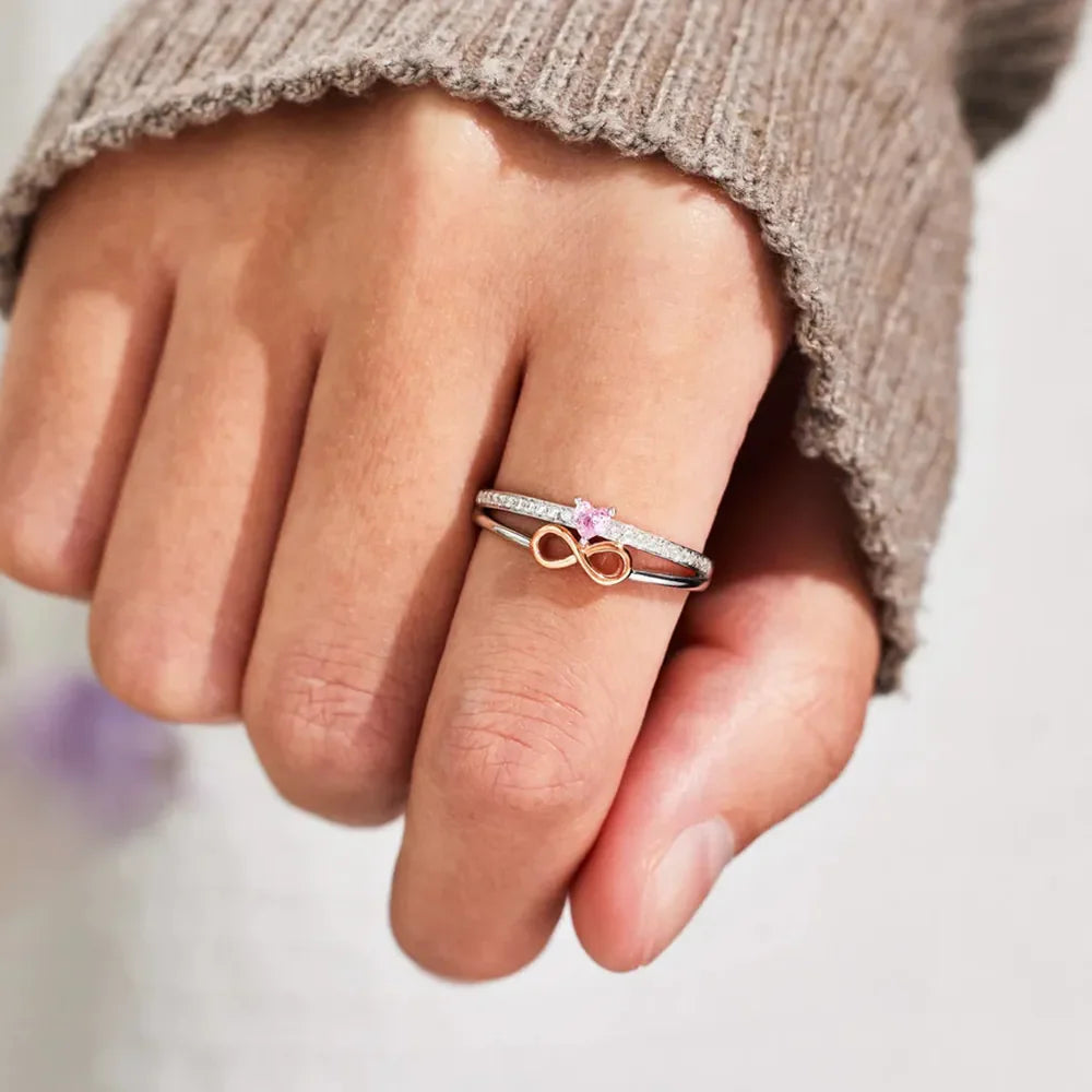 Silver infinity heart ring set with pink stone and pave band detail.