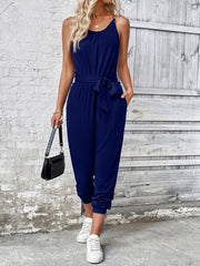 Dark blue chain-strap gathered waist jumpsuit with tie belt and cuffed ankles.