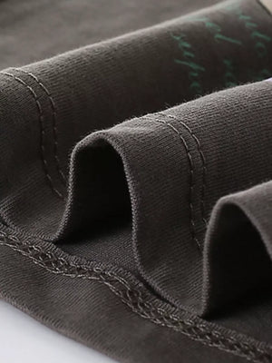 Toddler t-shirt in dark gray cotton with visible stitching and a subtle green graphic print.