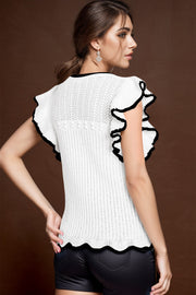 White knit ruffle top with black trim and scalloped hem.