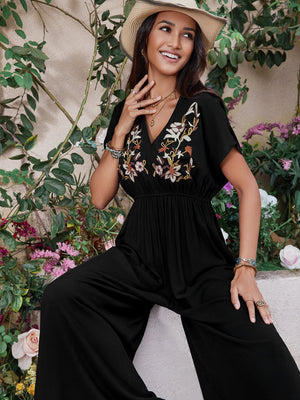 Black wide-leg jumpsuit with embroidered floral V-neck and flutter sleeves.
