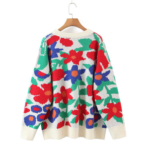 Floral intarsia crewneck knit sweater in white with red, blue, and green abstract floral pattern.