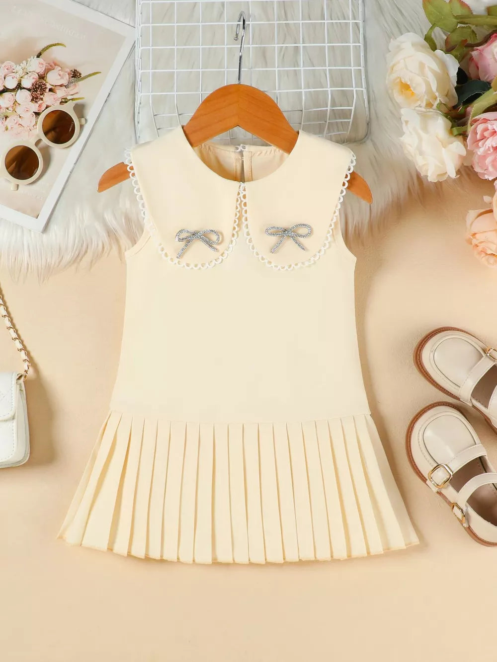 Apricot toddler dress with lace collar, two bows, and pleated skirt.