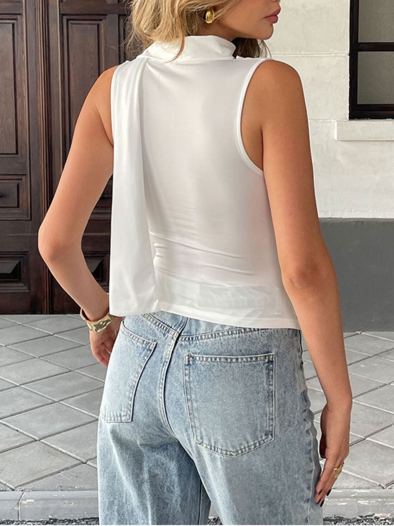 White draped cowl neck cami top with a flowing detail on the side.