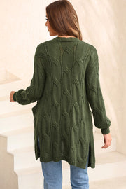 Green cable knit open-front cardigan with pockets and side slits.