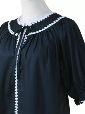 Black polyester blouse with scalloped collar, tie neck, and ruffled cuffs.