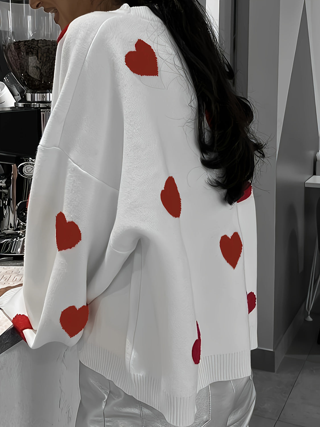 White oversized knit crewneck sweater with red heart pattern and drop sleeves.