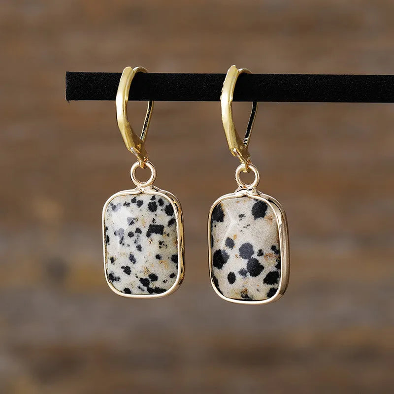 Gold-plated drop earrings with speckled stone pendants.